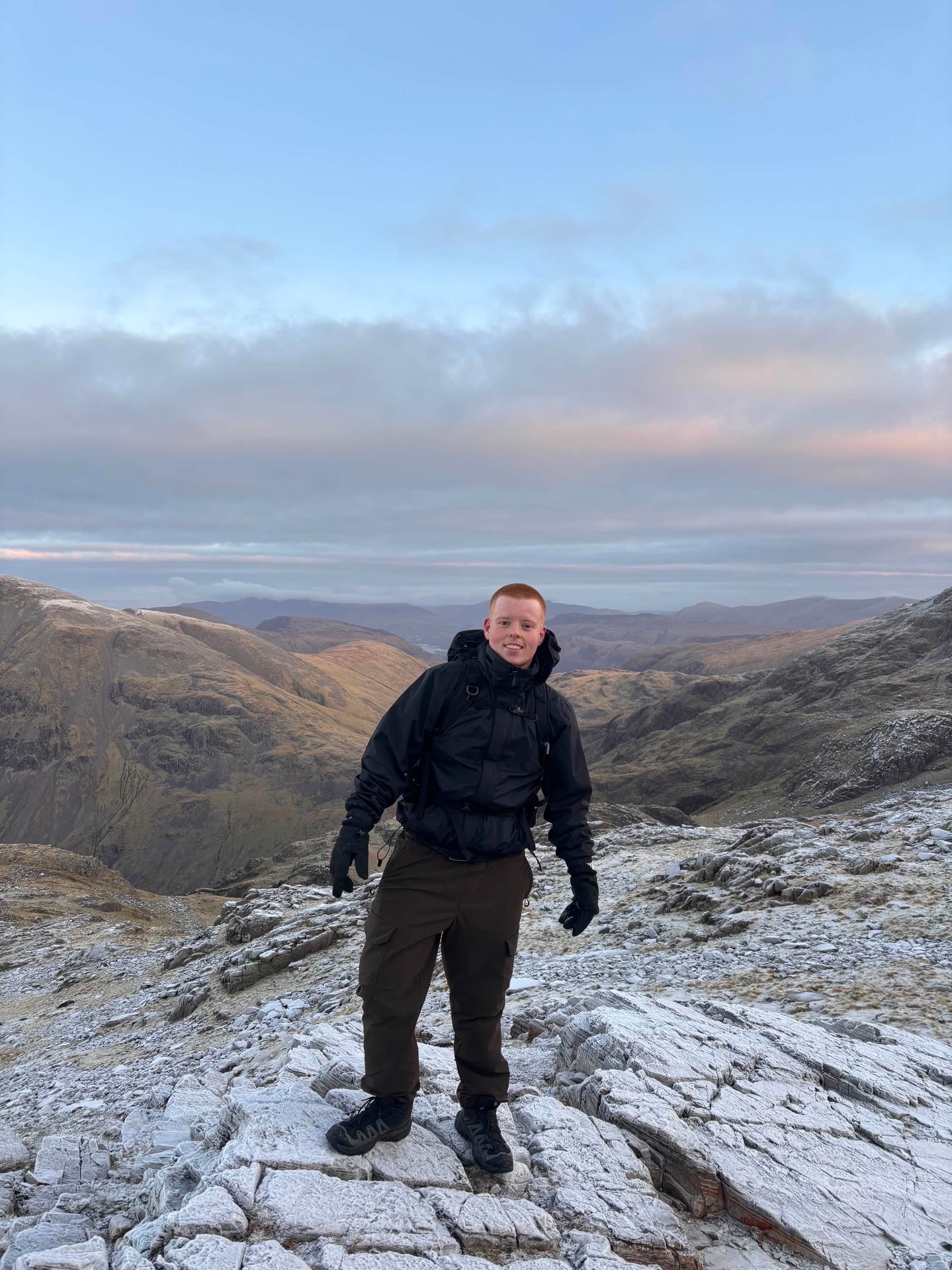 Sam on a snow-dusted mountain summit at sunrise